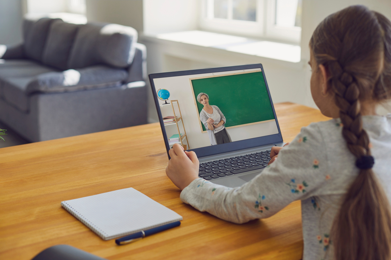 A student following a video lesson on a laptop at the kitchen table